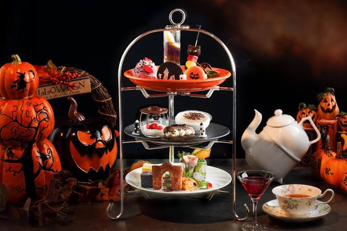 Afternoon high tea setup with tiered dessert stands and roses in a cafe.